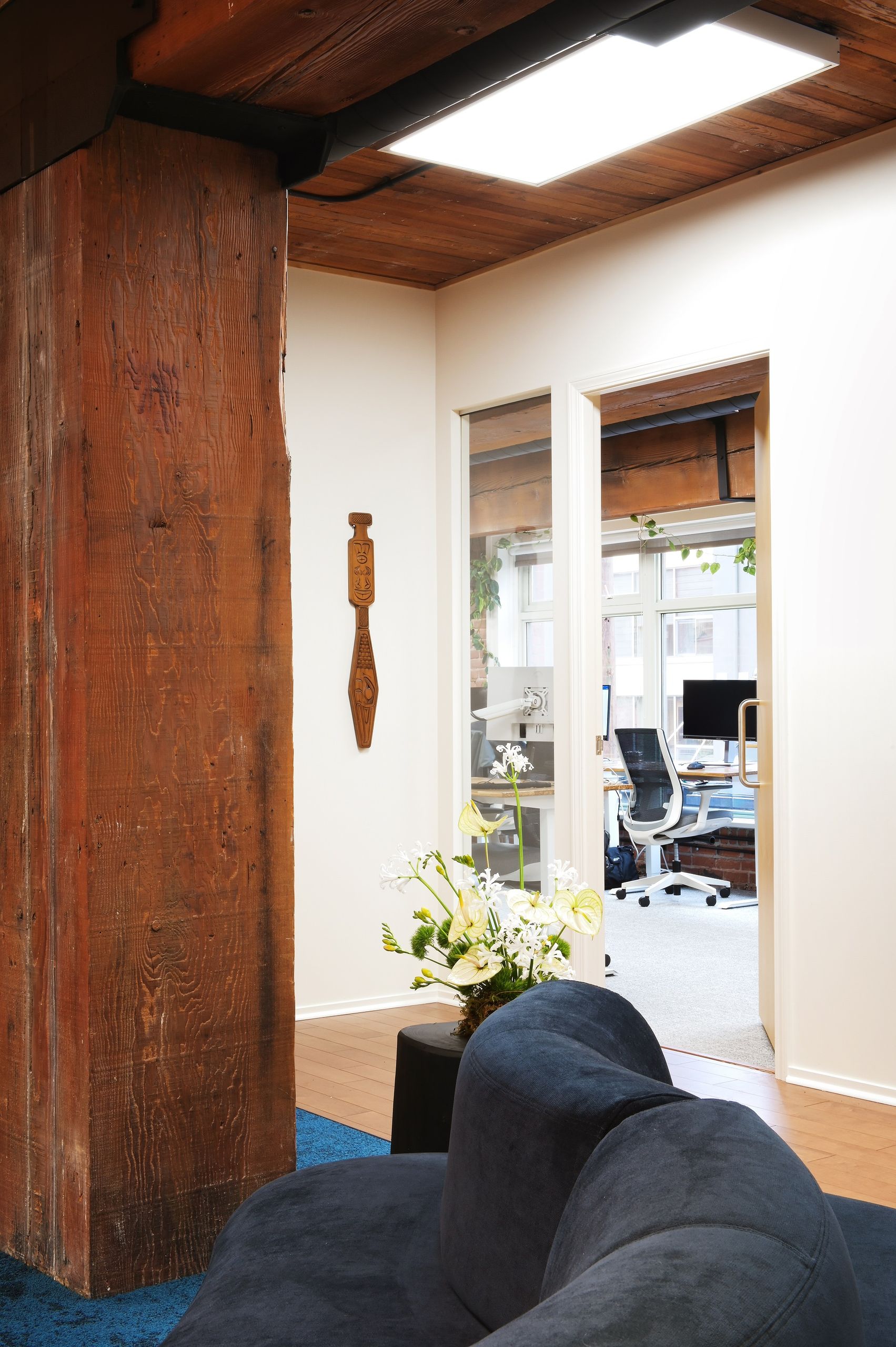 Reclaimed timber column and carved figure beside the doorway to the open workspace
