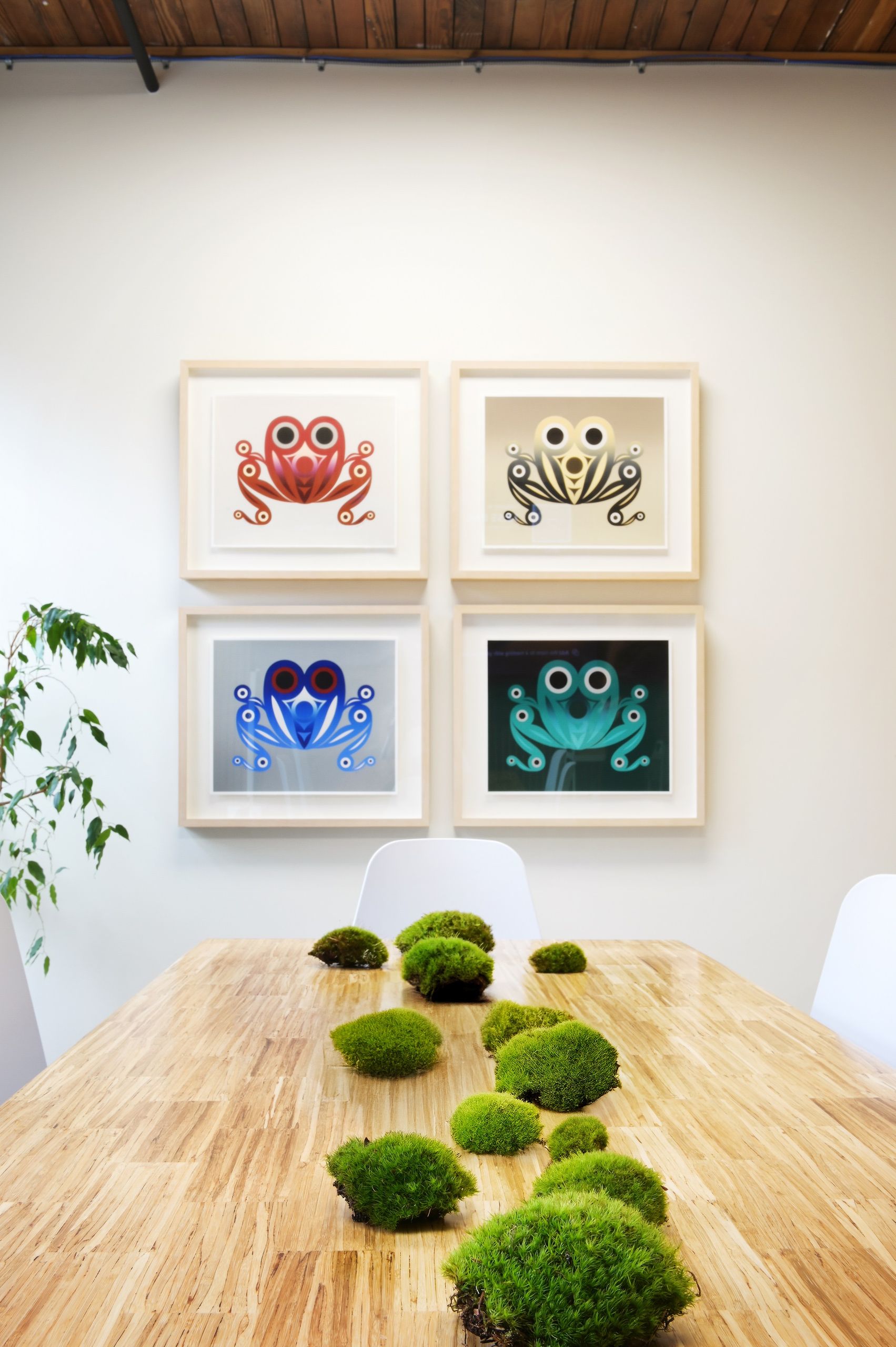 Four framed Northwest Coast frog prints above the moss-topped meeting table