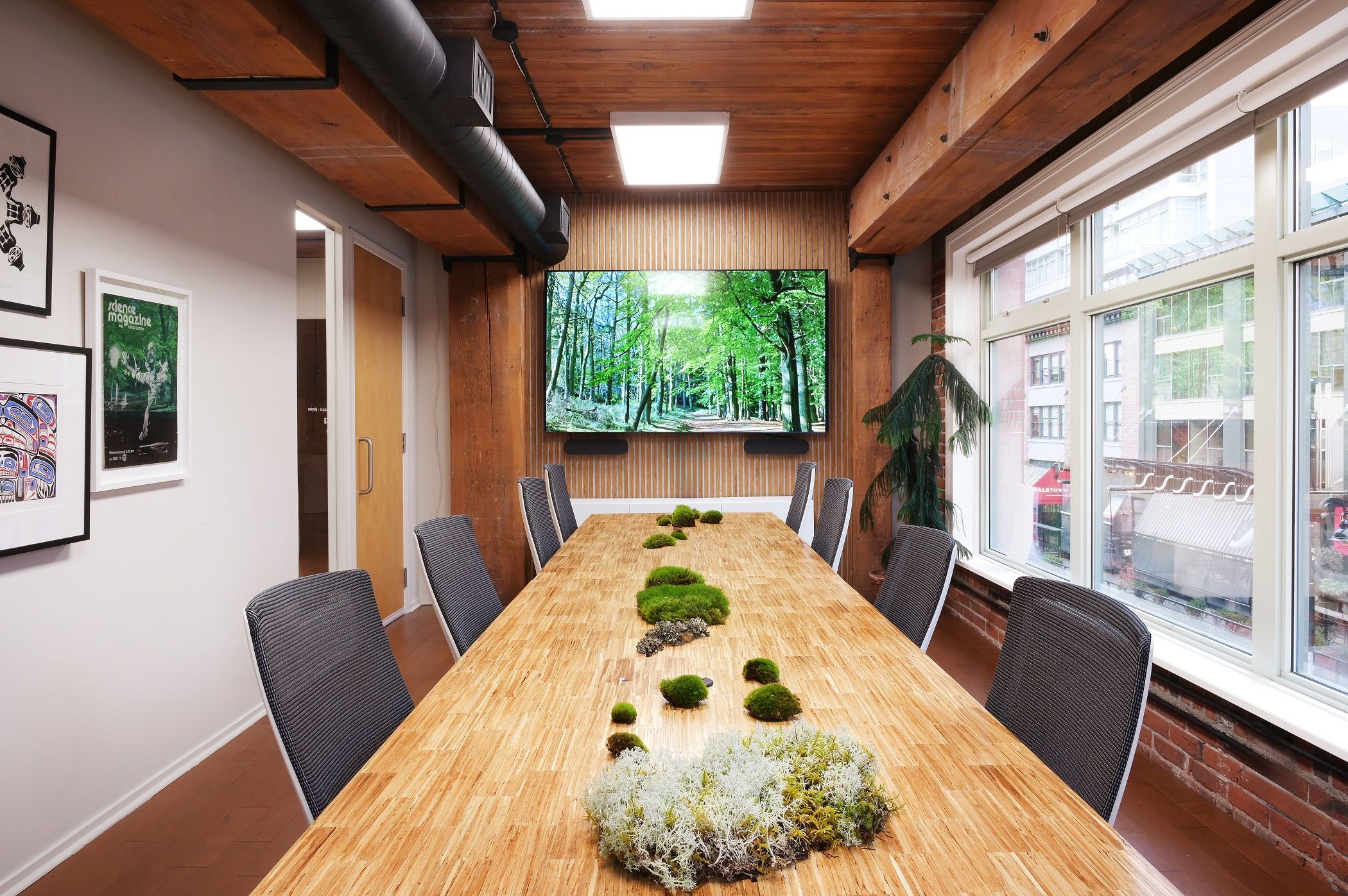 Boardroom looking toward a screen on slatted wood, with framed artwork lining the side wall