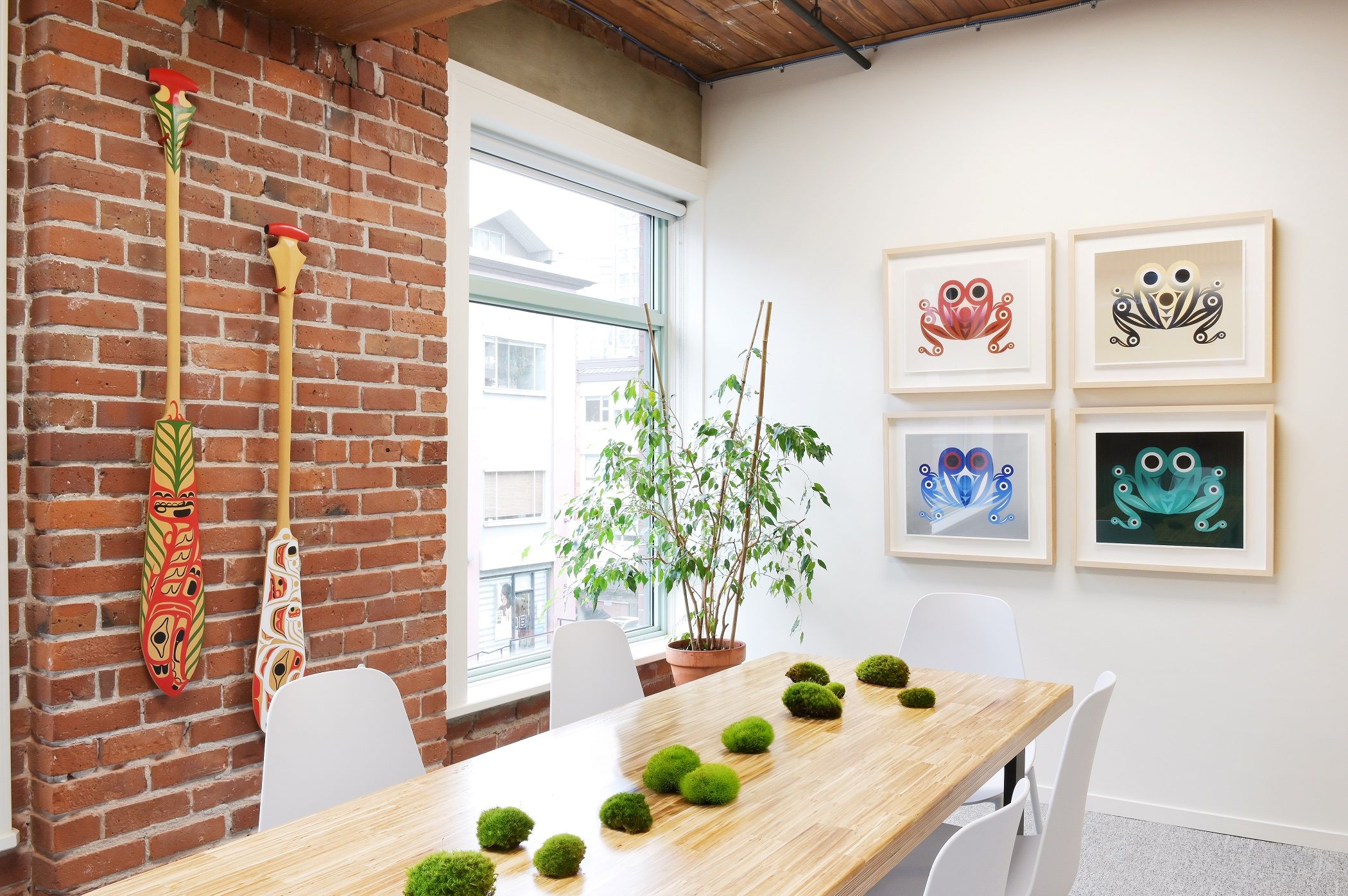 Meeting room with carved paddles on brick and four frog prints on the facing wall