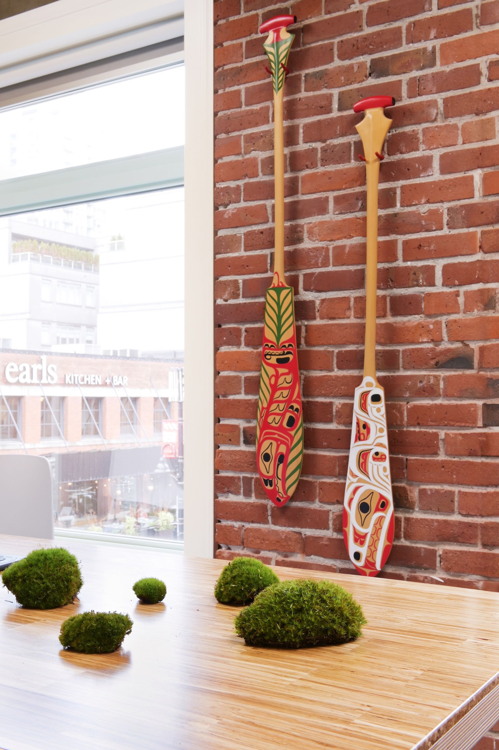 Detail of two carved and painted paddles mounted on the original brick wall