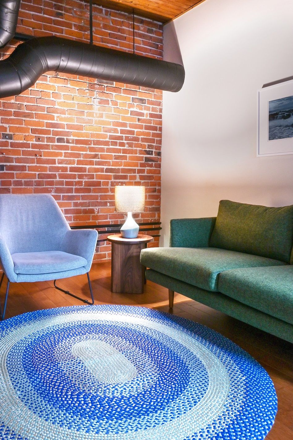 Quiet seating corner with a green sofa, pale blue armchair and braided blue rug