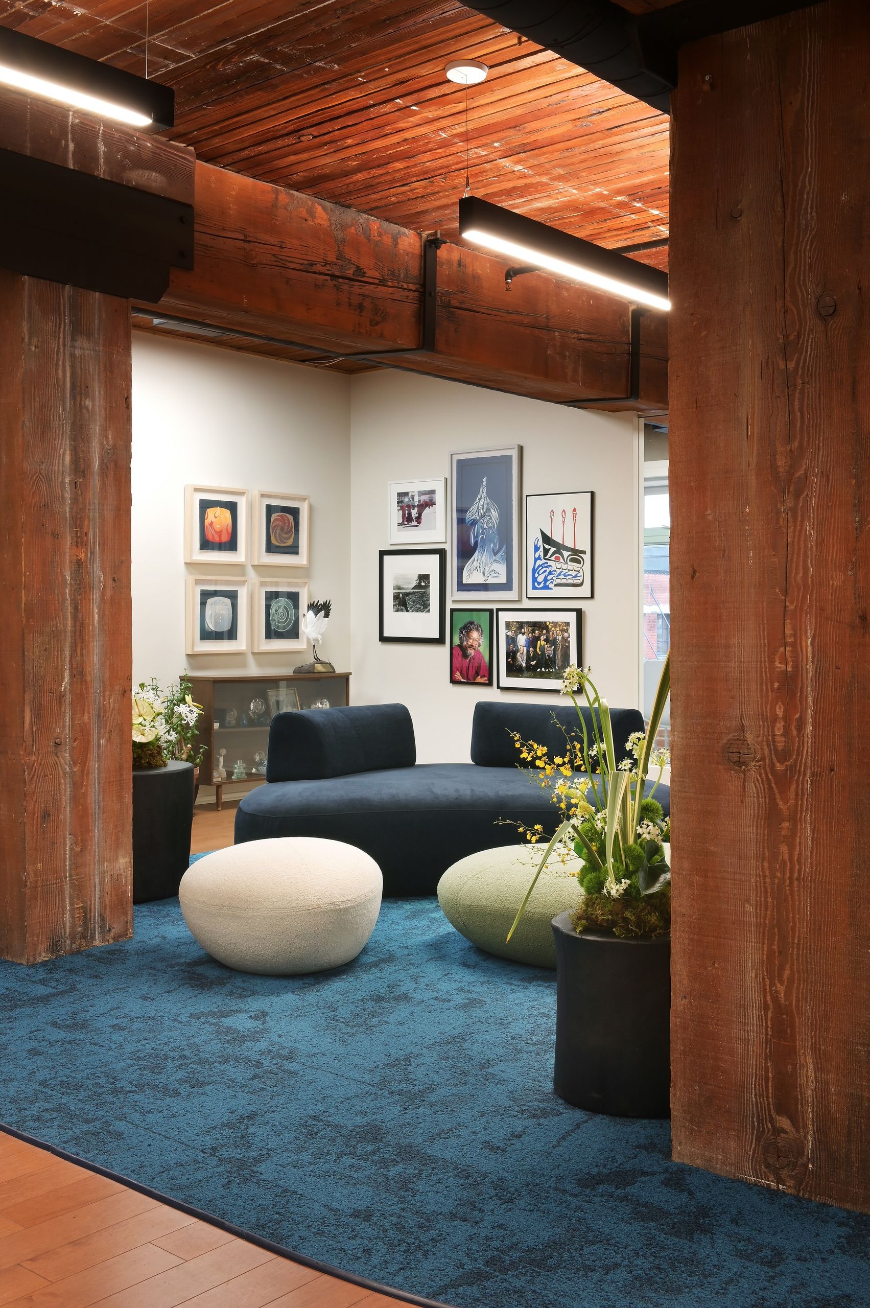 The lounge framed between heavy reclaimed timber posts, with a blue-green carpet inset