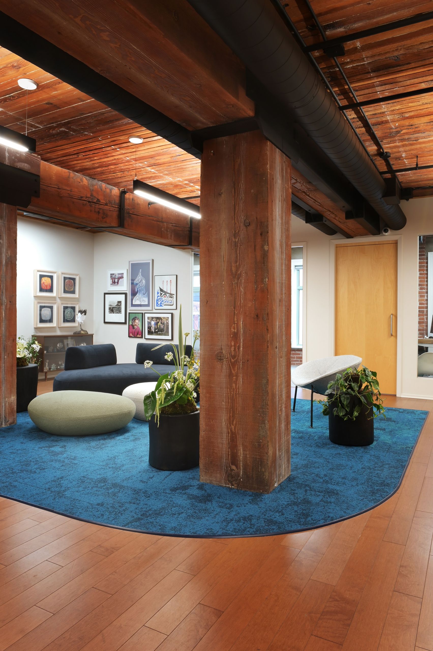 Lounge seating and poufs arranged on the curved carpet inset among the timber columns
