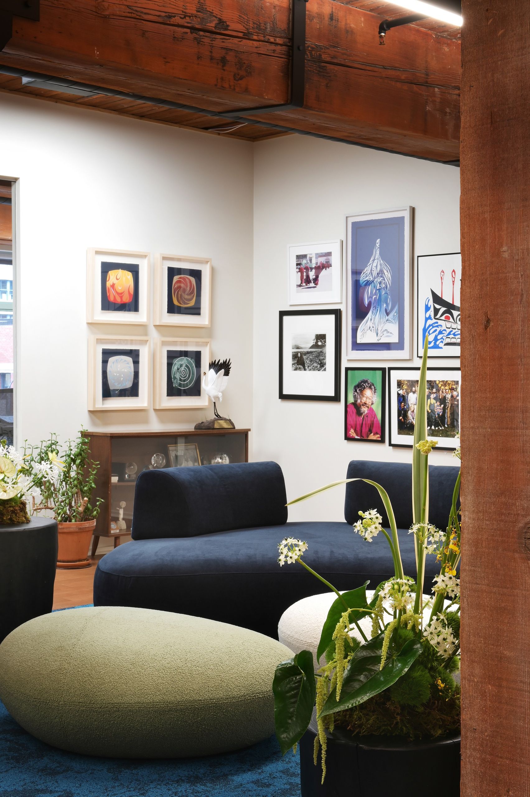 Lounge corner with framed prints above a mid-century cabinet and a crane sculpture