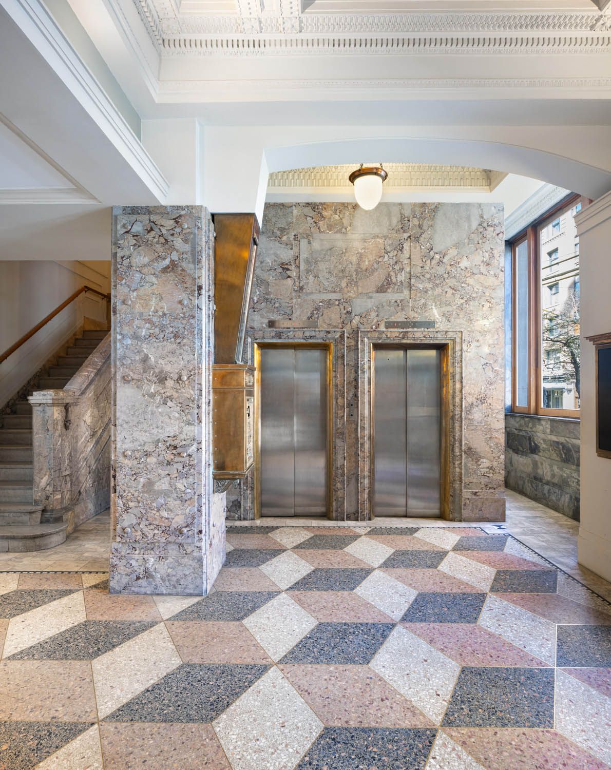 Heritage lobby with fossil marble walls, brass-trimmed lifts and a geometric terrazzo floor
