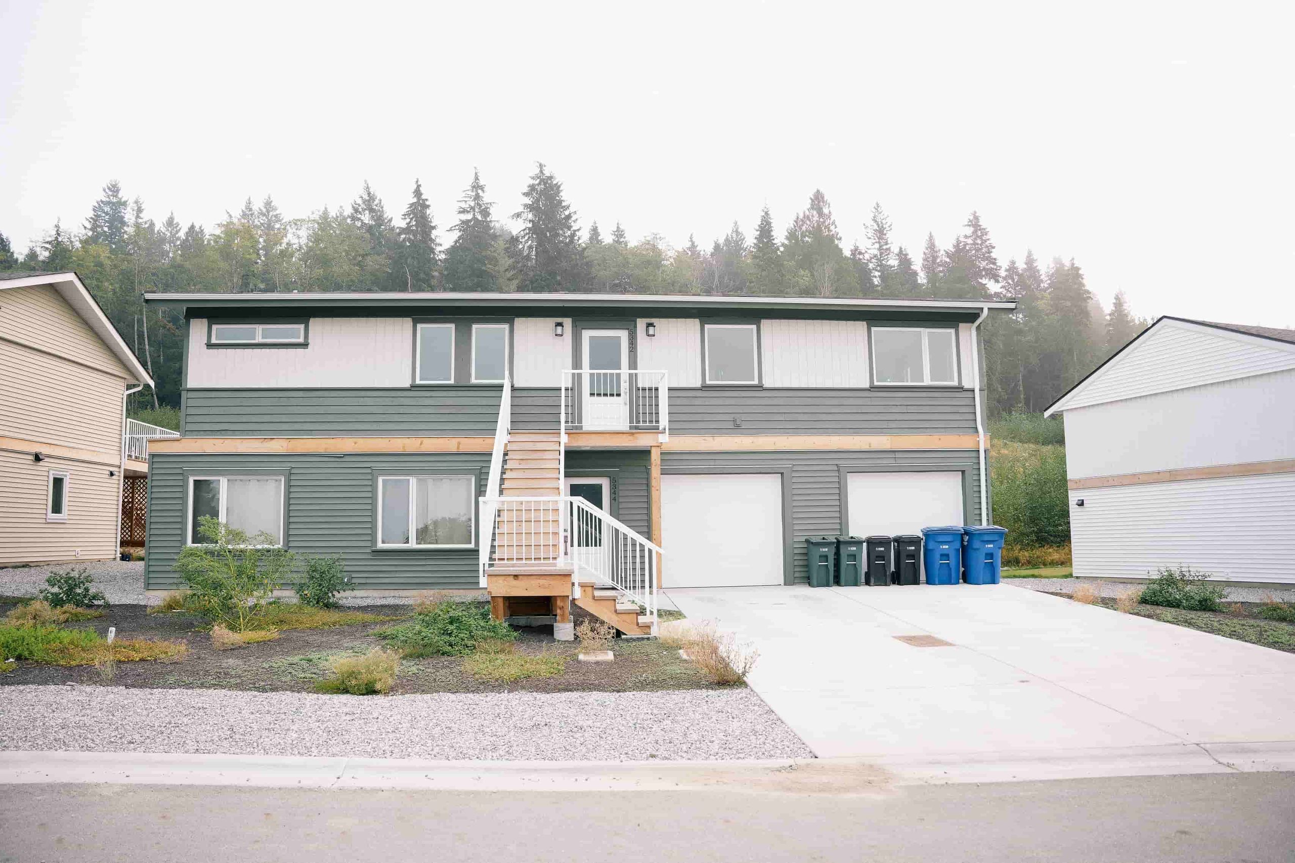 Street elevation of a relocated home lifted onto a newly built lower suite with two garages