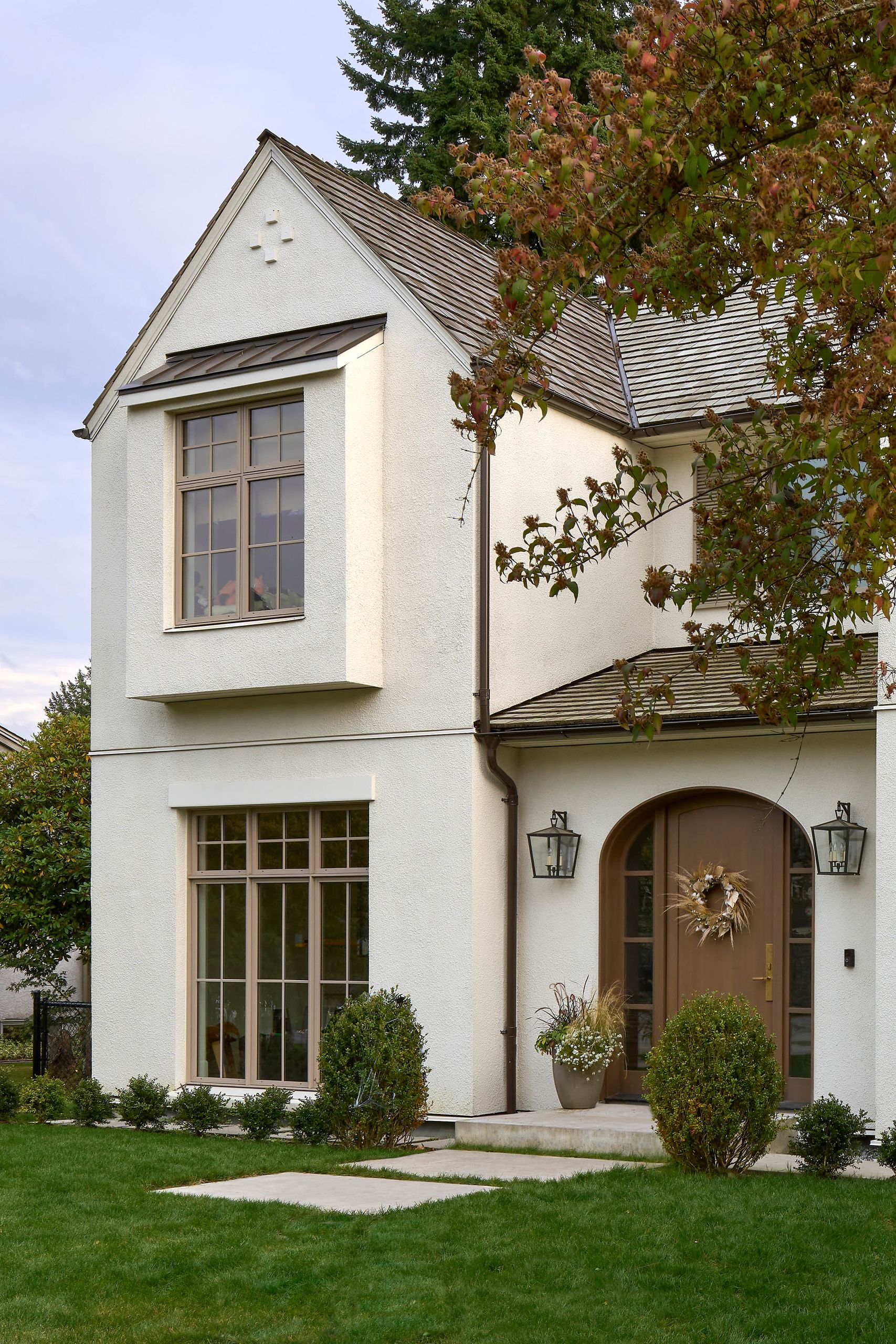 Gable end and projecting bay window seen past a dogwood in autumn colour