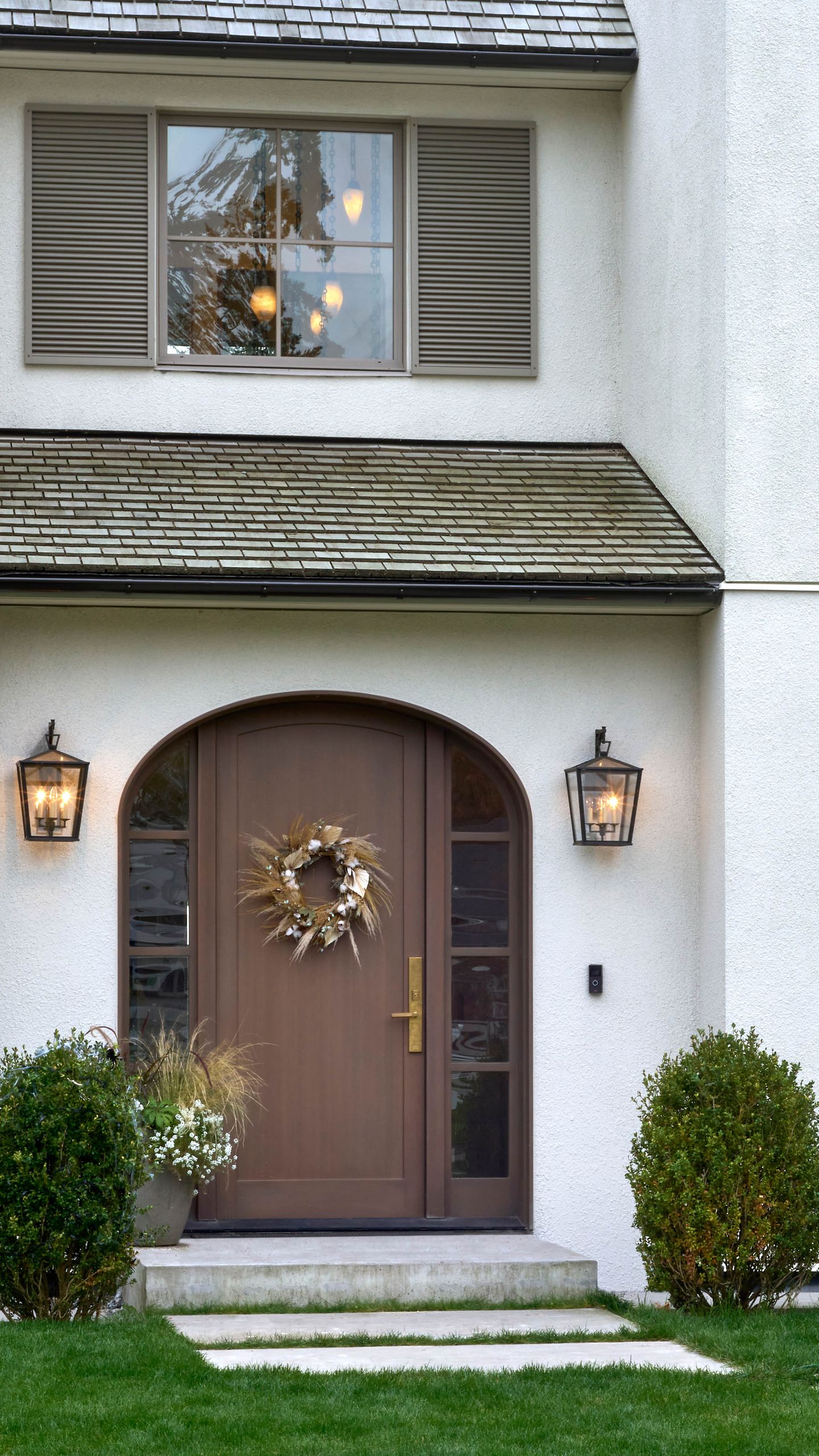 Entry bay with its shingled pent roof, lanterns and clipped boxwood