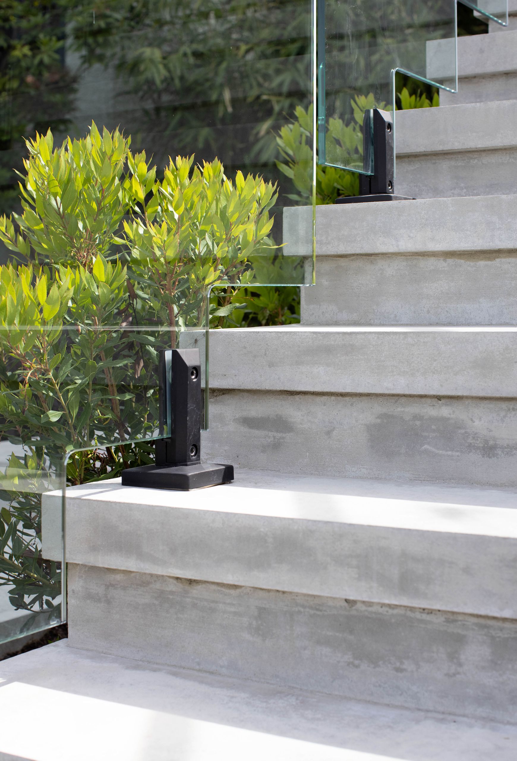 Detail of the concrete treads and the black spigots holding the glass balustrade
