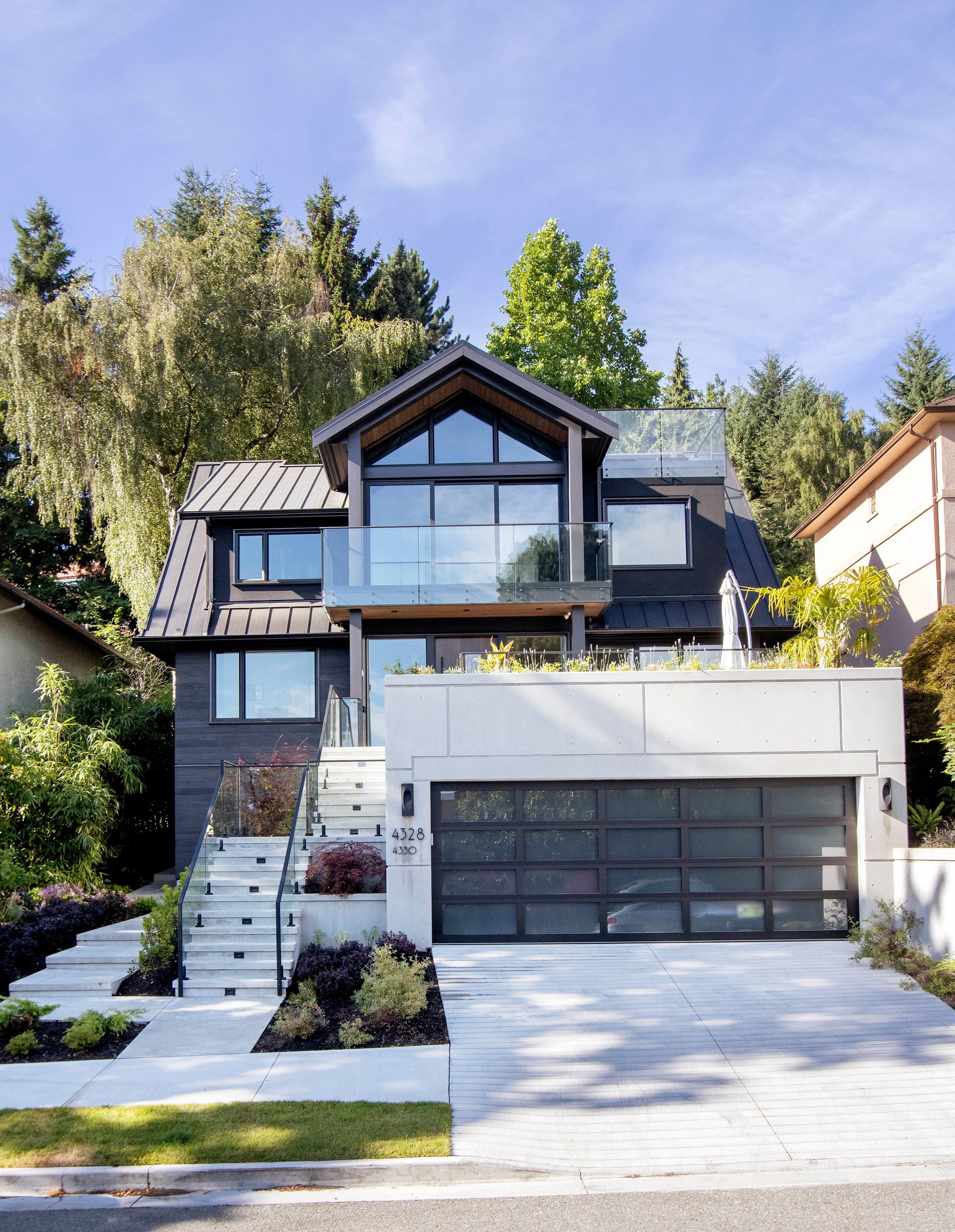 Full street elevation of the three-storey house above its concrete garage and planted terrace