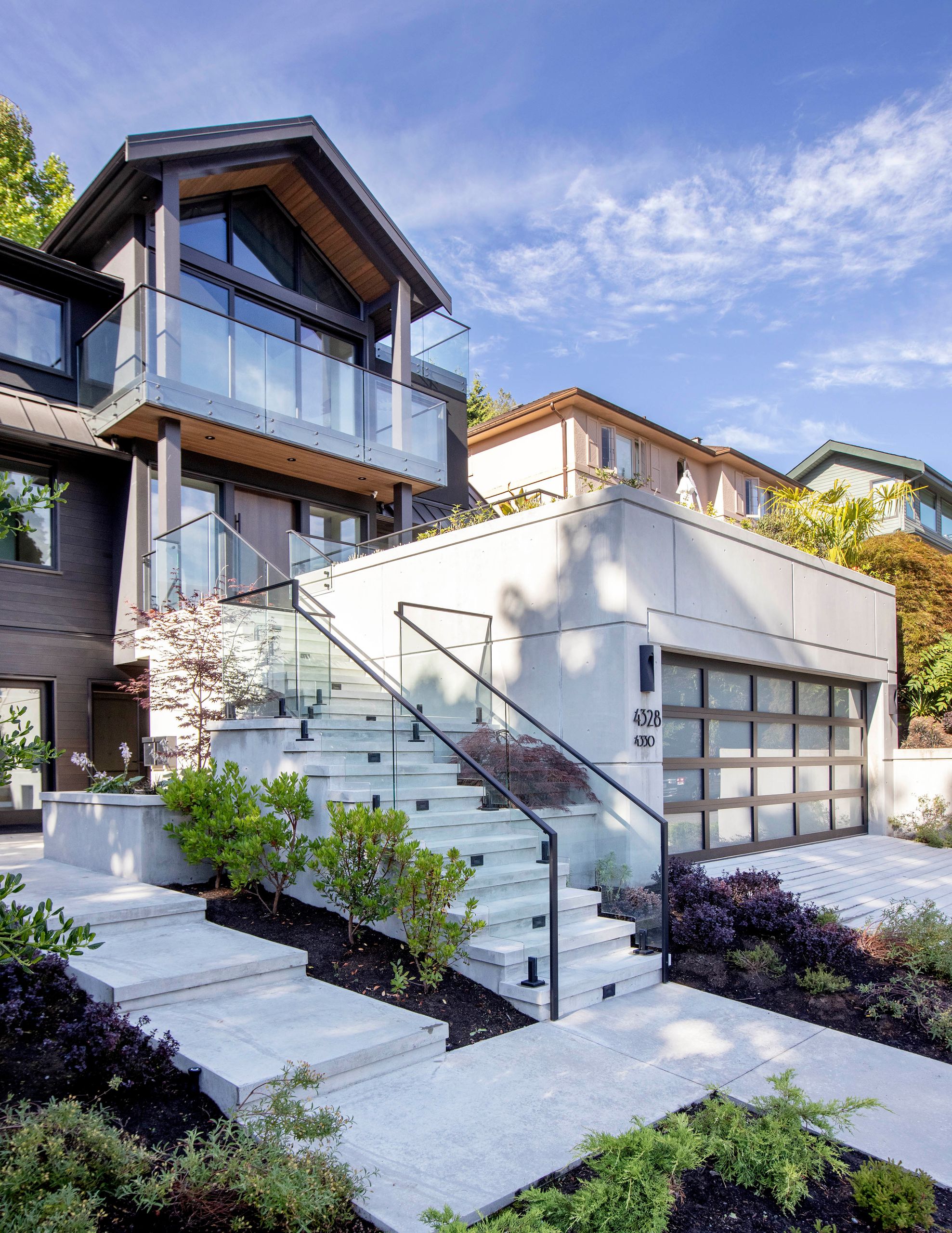 Three-quarter view of the entry, glass balconies and concrete stair from the driveway