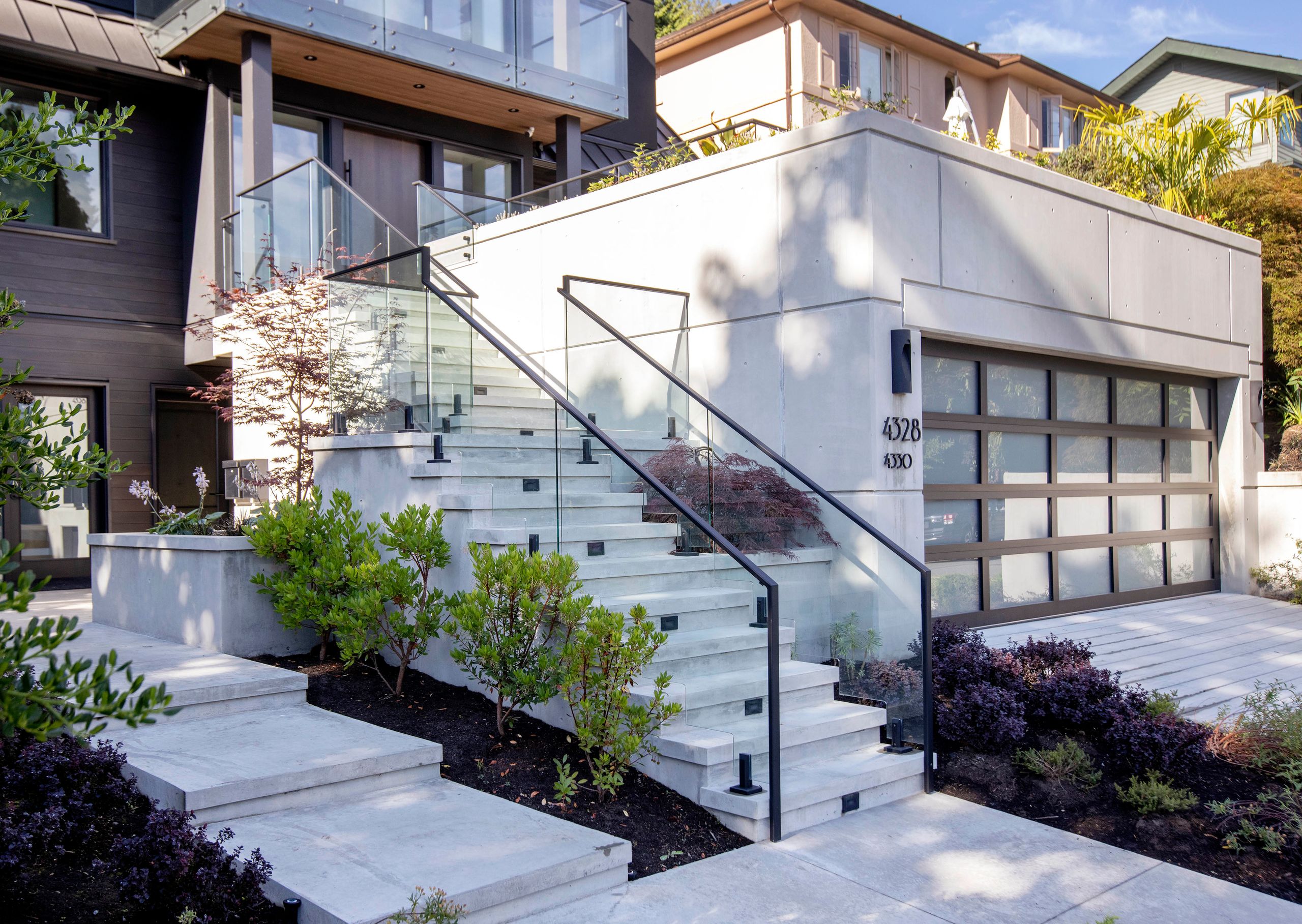 Board-formed concrete entry stair rising past the garage volume to the front door