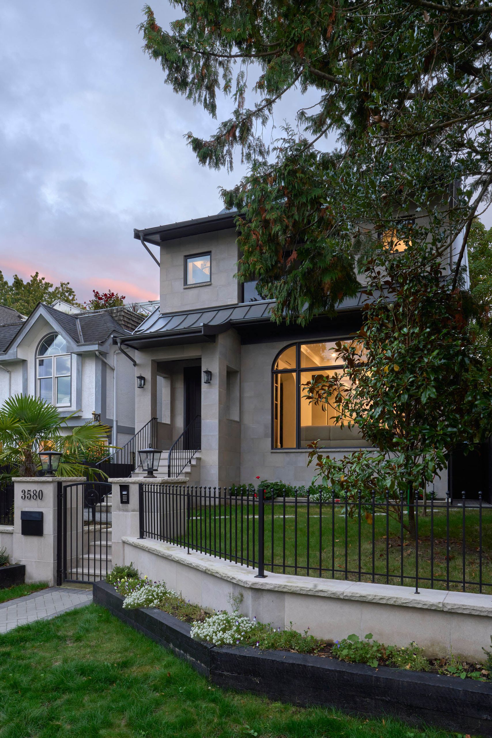 The house at dusk with the arched window lit from within