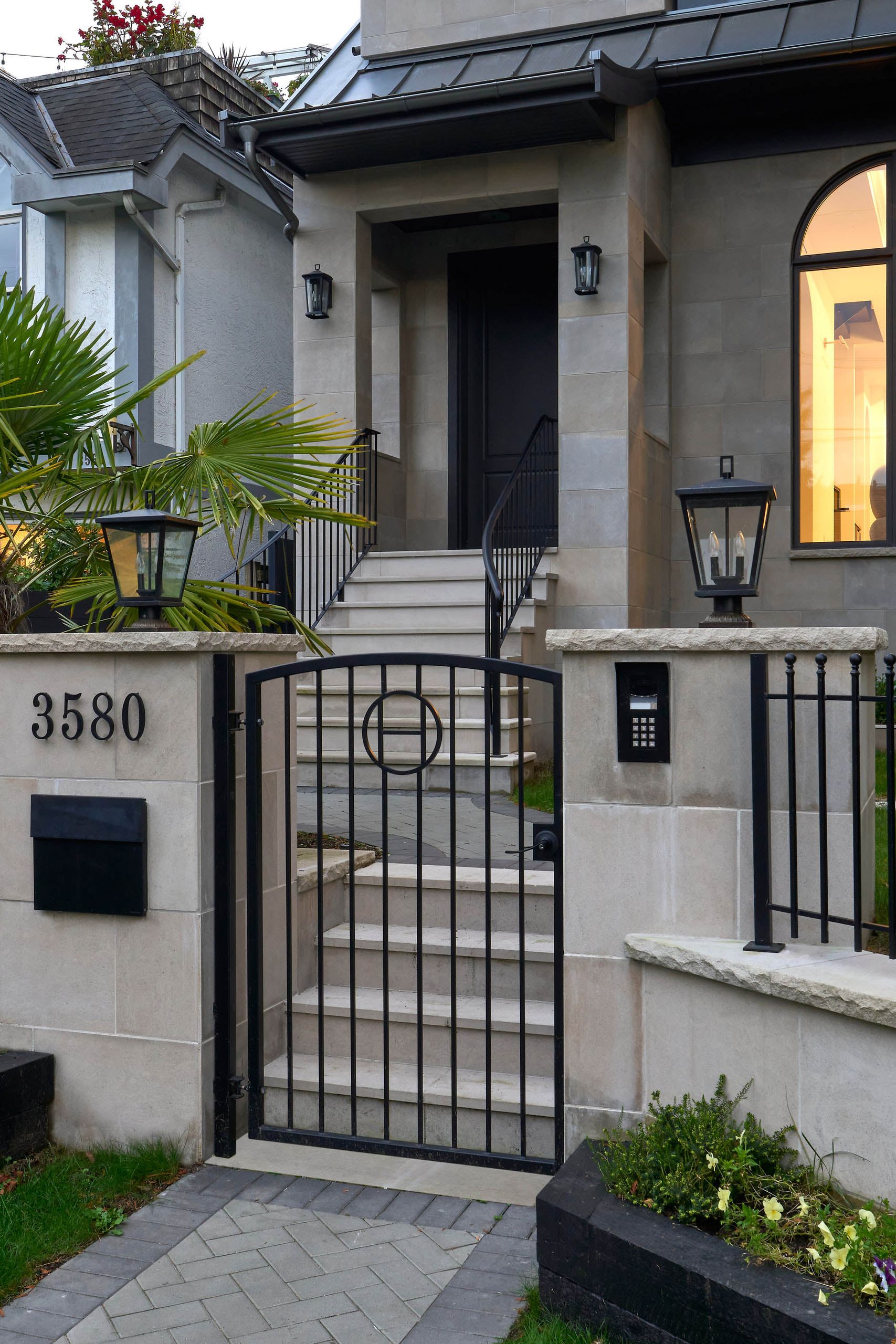 Iron entry gate with a circle motif between lantern-topped stone piers