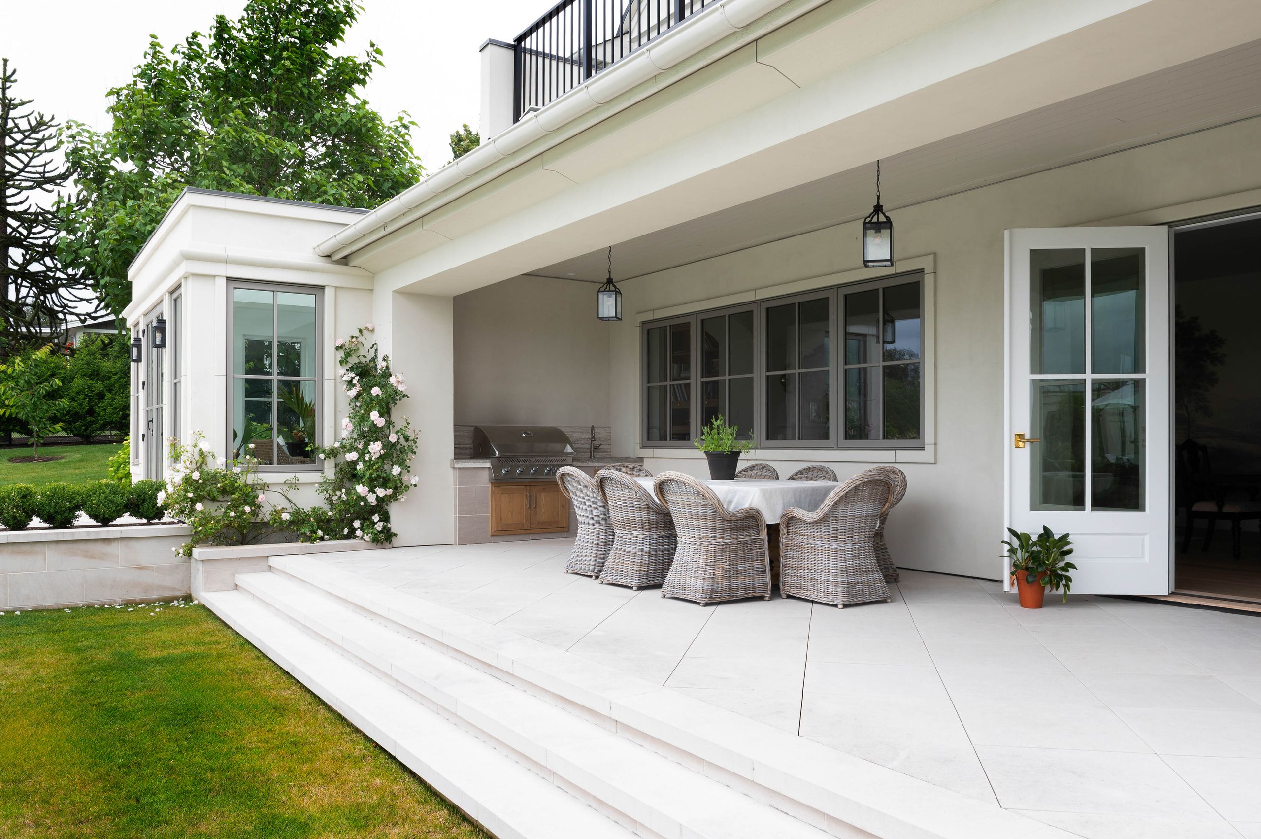 Loggia dining terrace with lantern pendants and a built-in grill