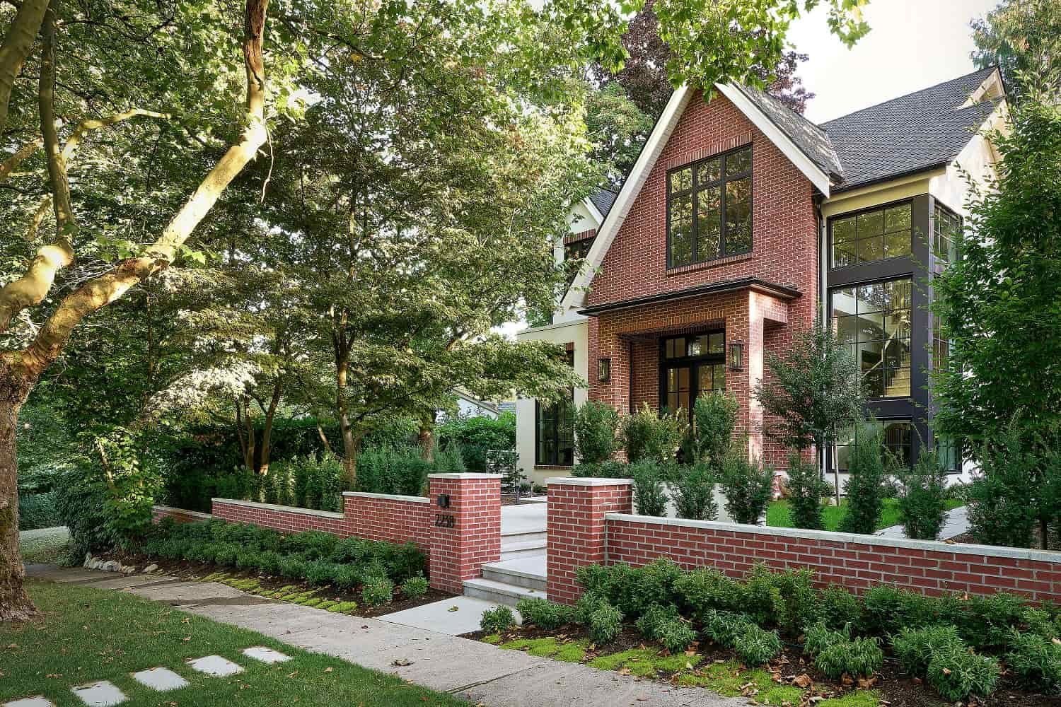 Three-quarter street view of the gabled brick facade and low brick garden wall