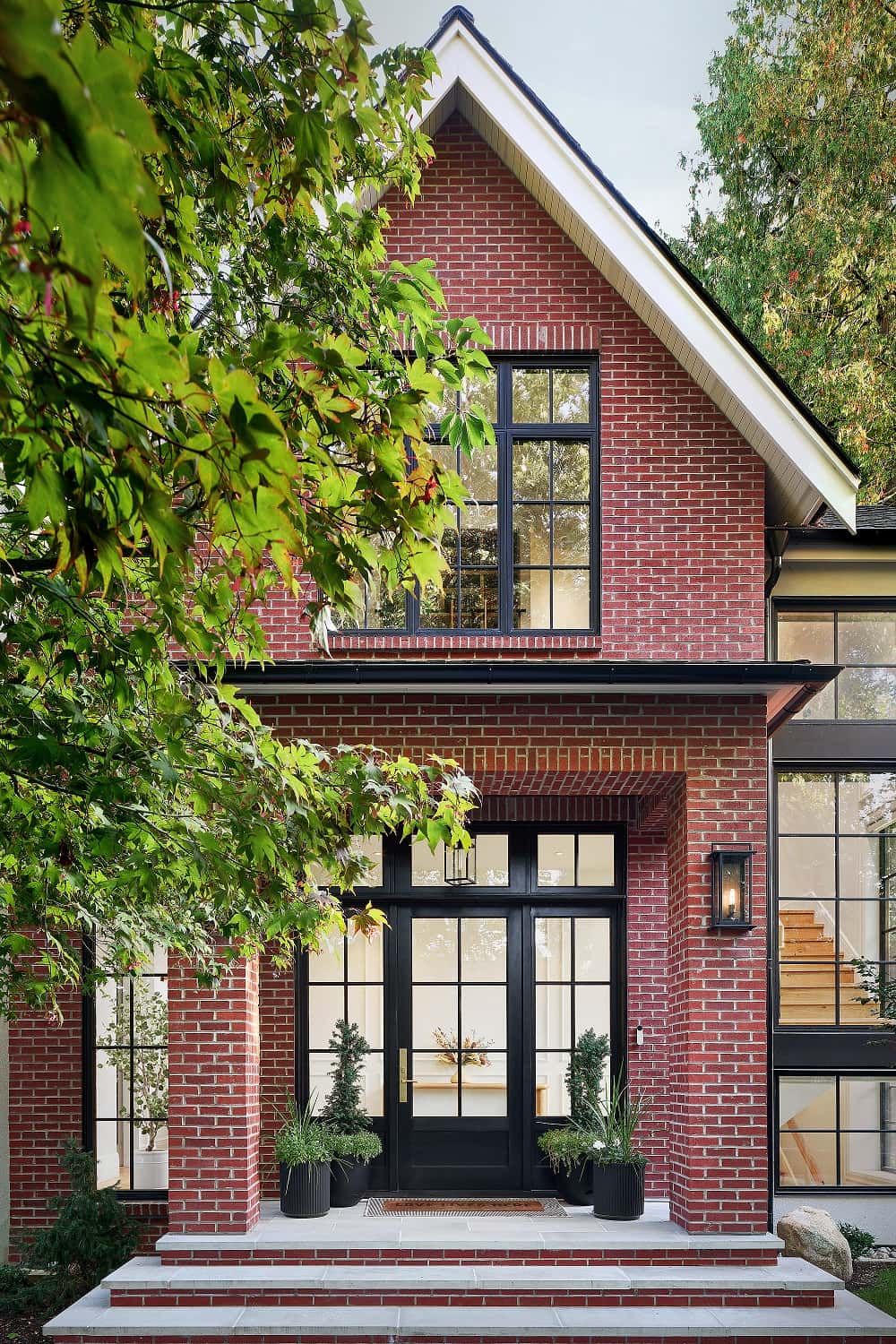 Covered entry beneath the gable, with the interior stair visible through tall windows