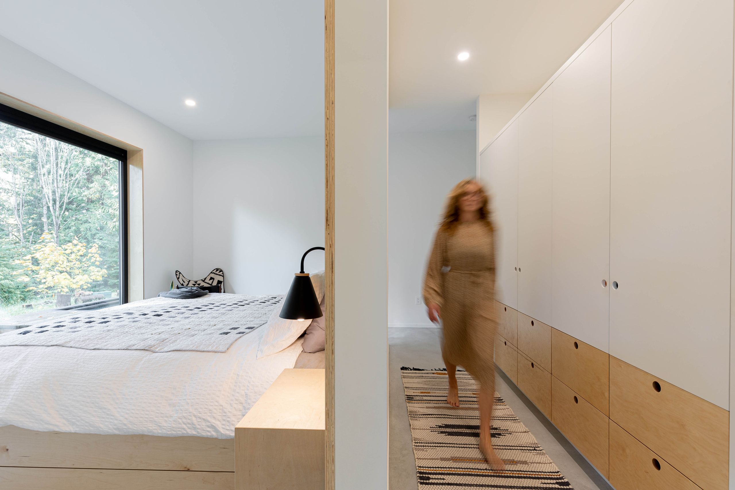 Dressing corridor of full-height plywood wardrobes leading through to the bedroom
