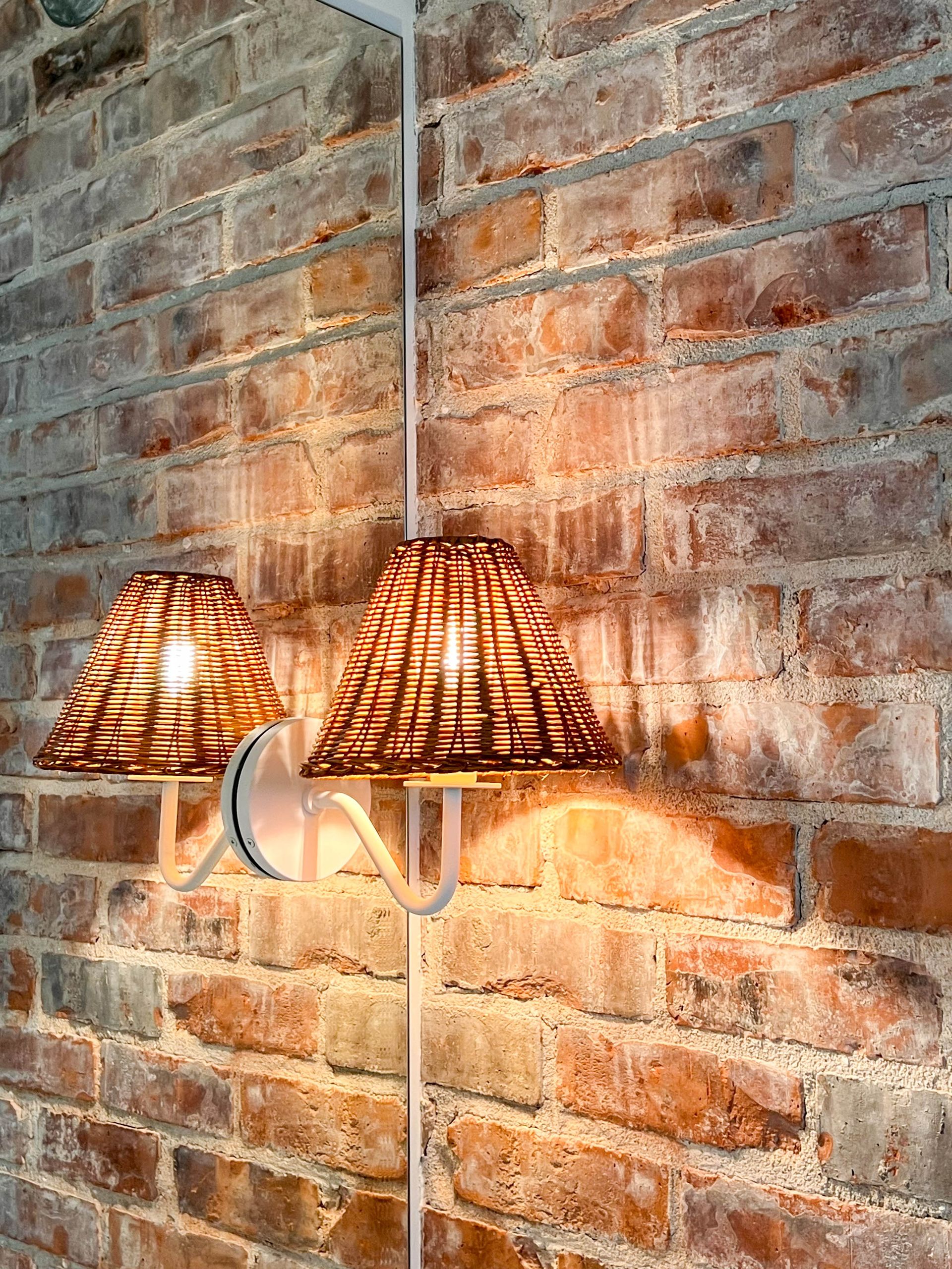 Pair of rattan-shaded sconces mounted on the original exposed brick wall
