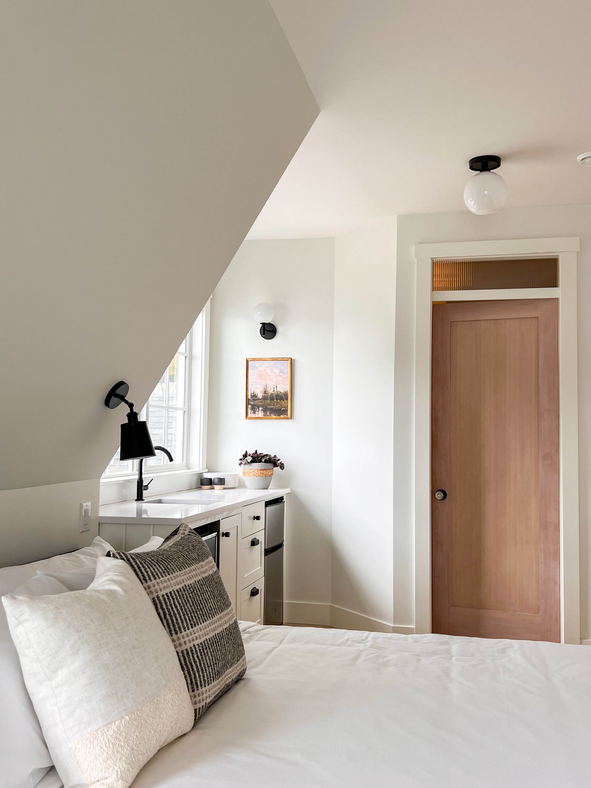 Guest suite under the dormer, with a kitchenette below the window and a stained wood door