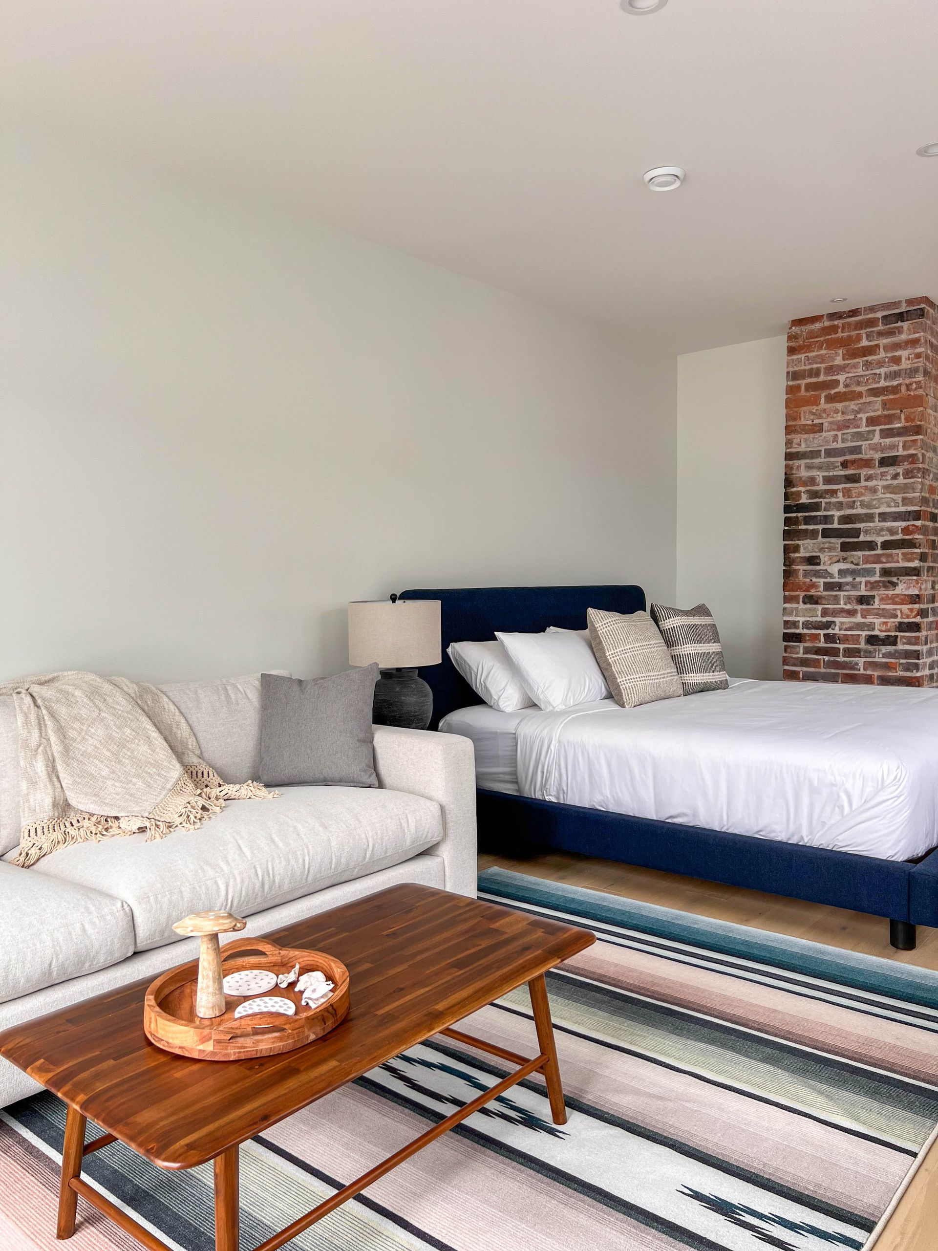 Suite with a navy upholstered bed set against the exposed brick chimney