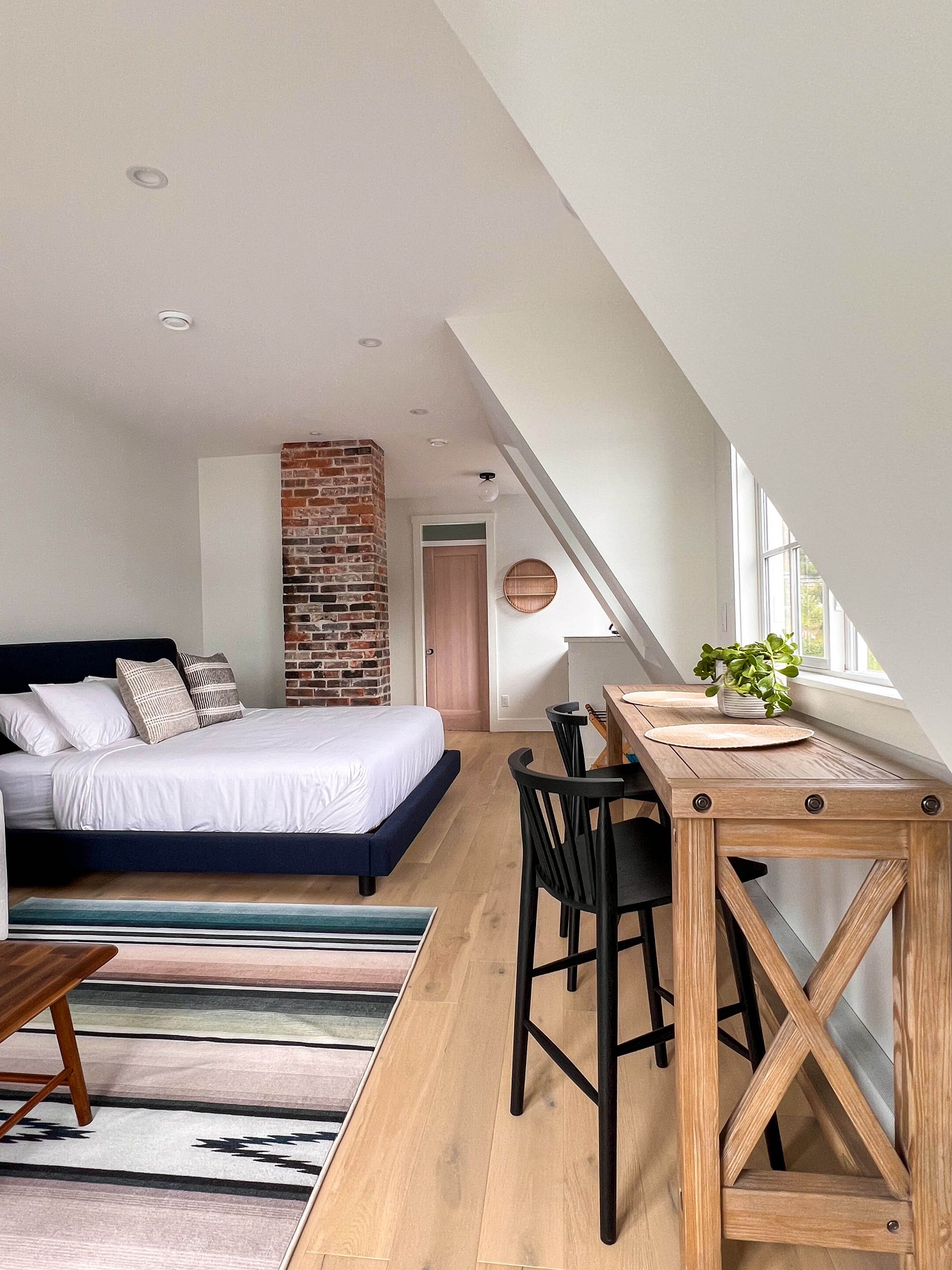 Suite looking past the brick chimney to the dormer window counter and stools