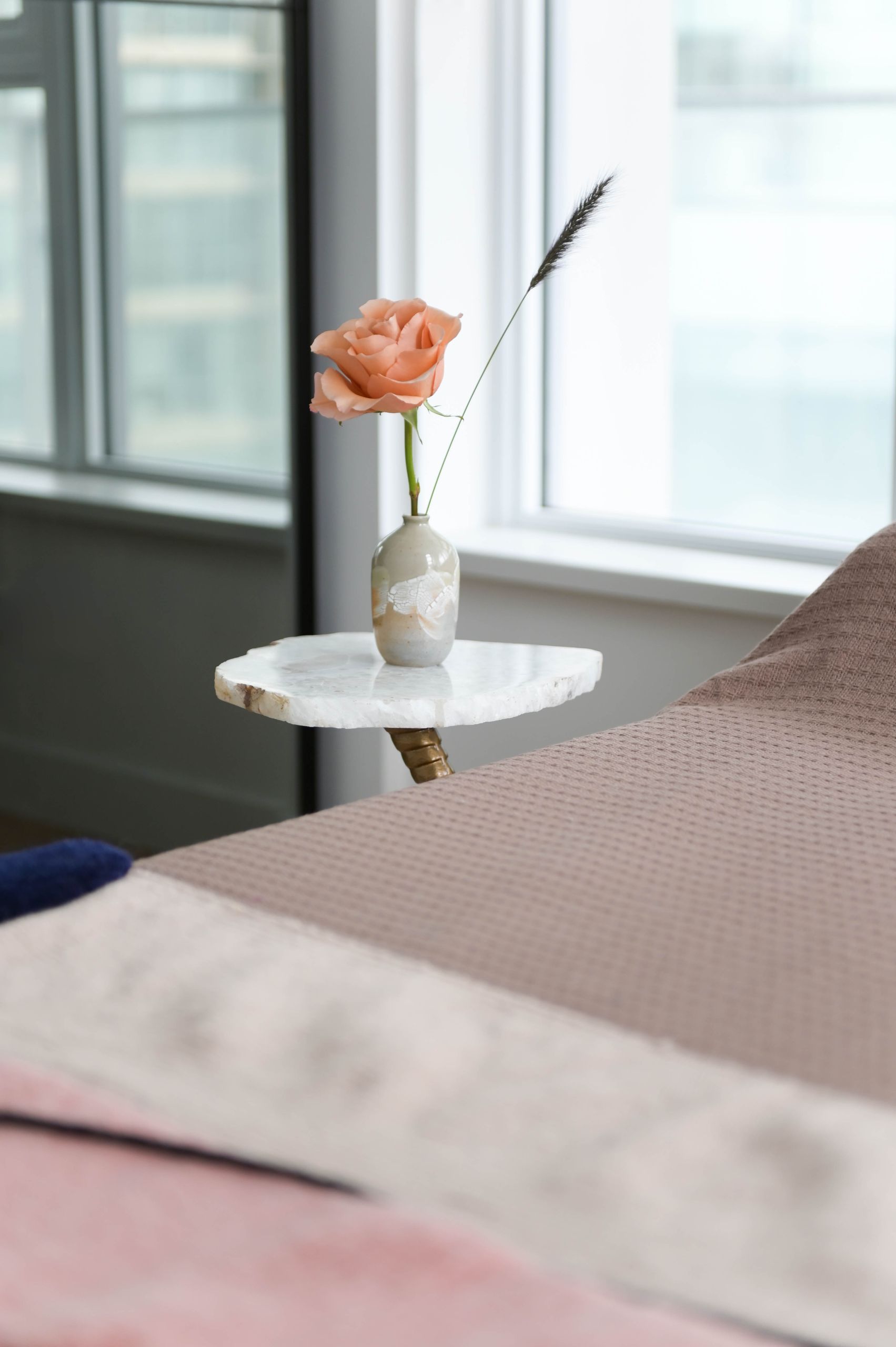 Agate-topped side table on a brass base holding a single peach rose