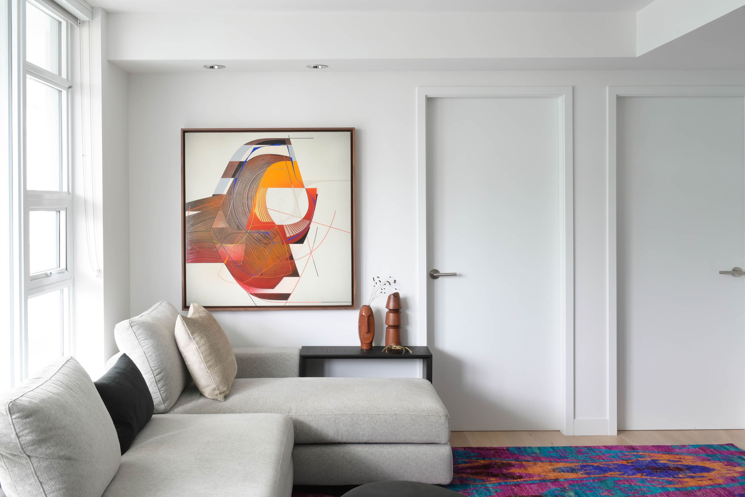 Living room with a grey sectional beneath a large abstract canvas in rust and orange