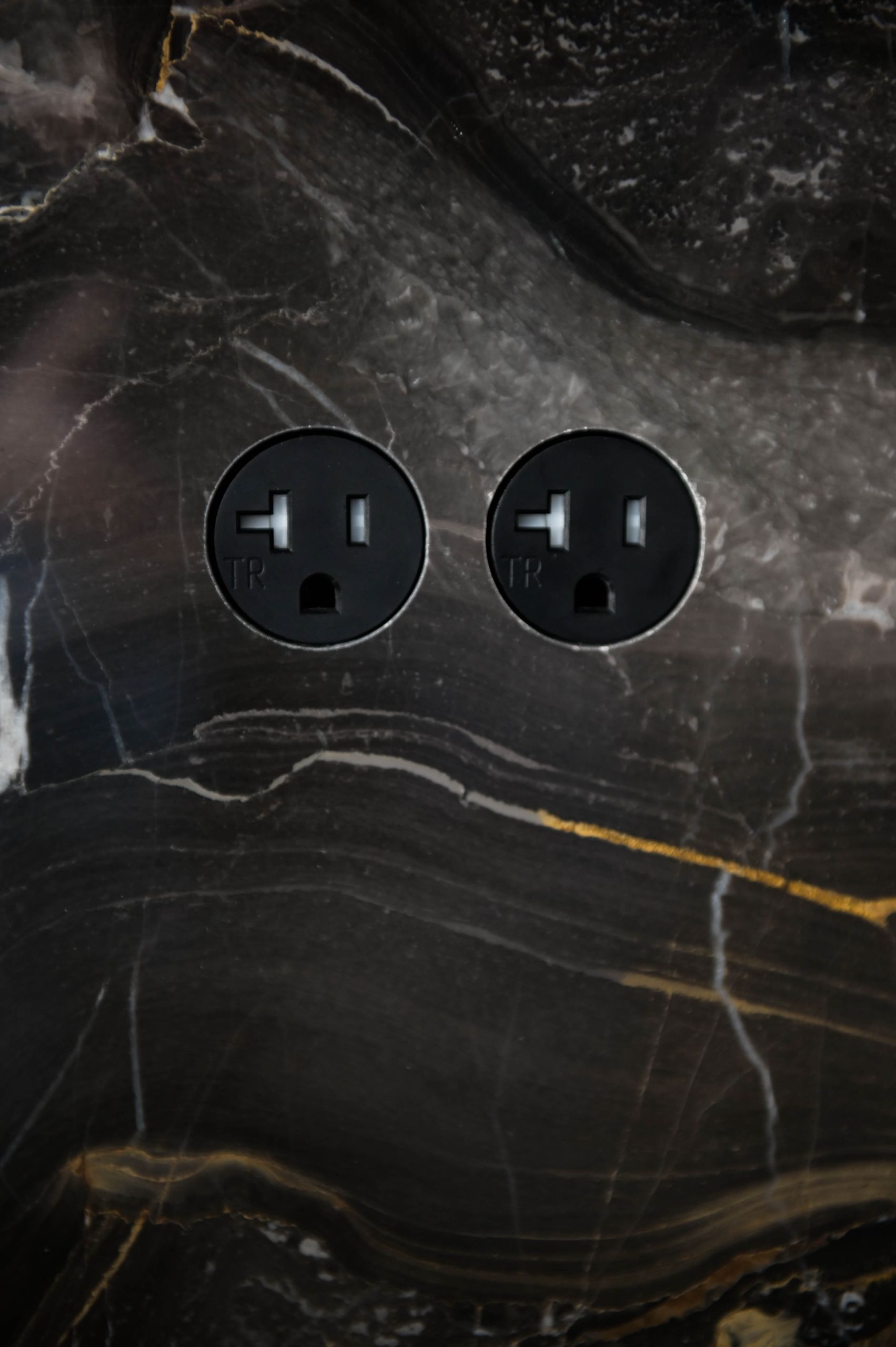 Outlets set flush into the veined marble backsplash