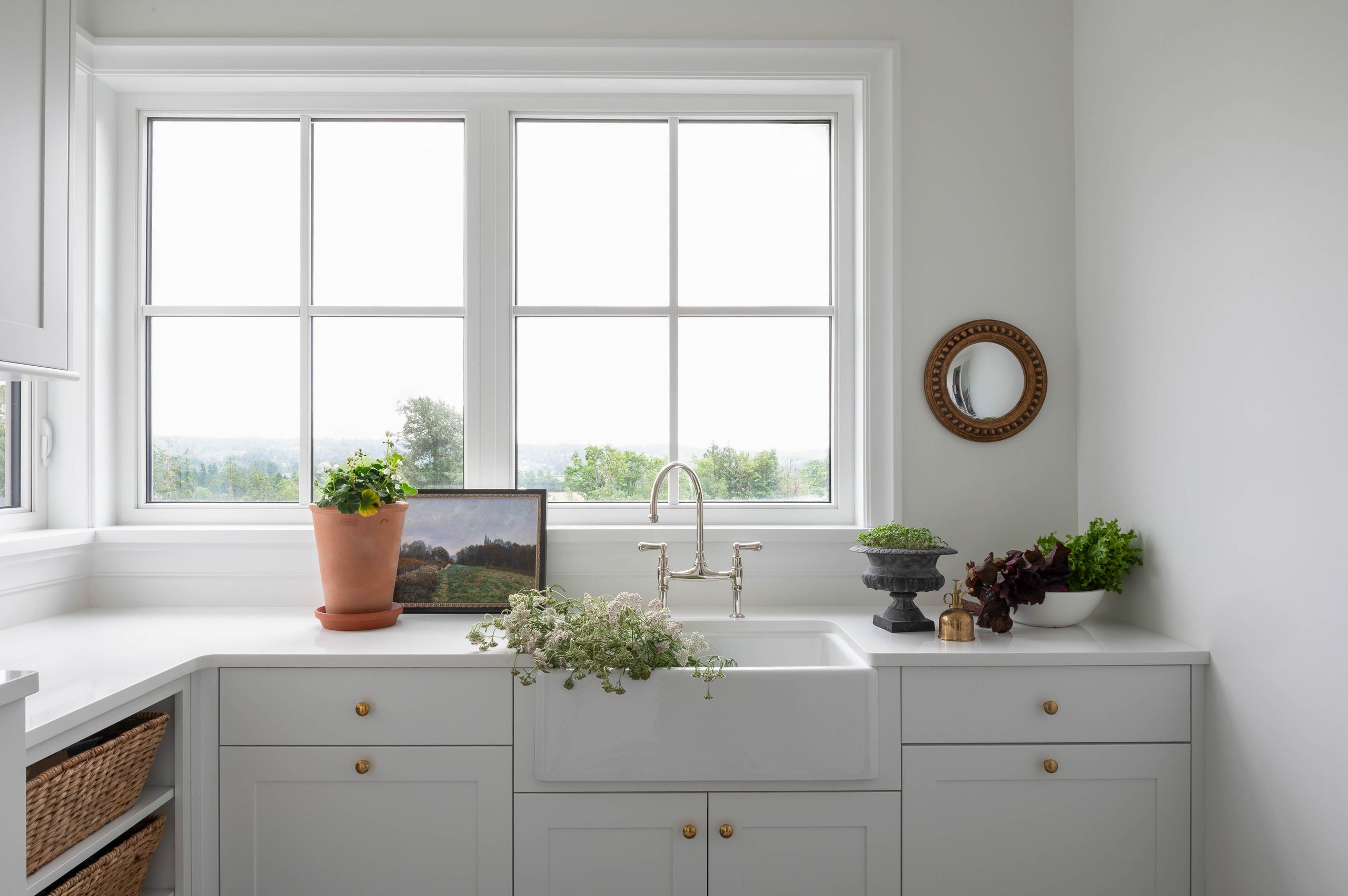 Scullery with pale grey cabinetry and a farmhouse sink below twin windows