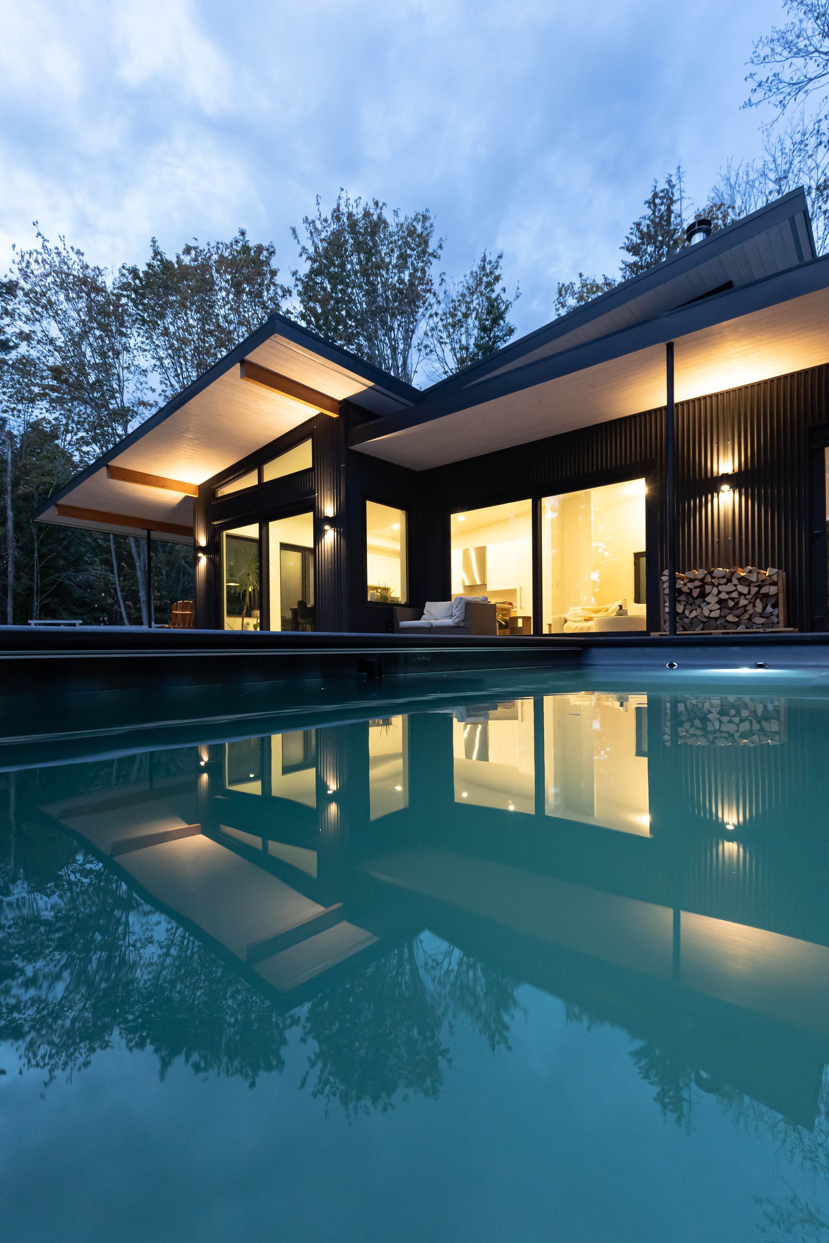 The pool mirroring the lit house and its butterfly roof after sunset