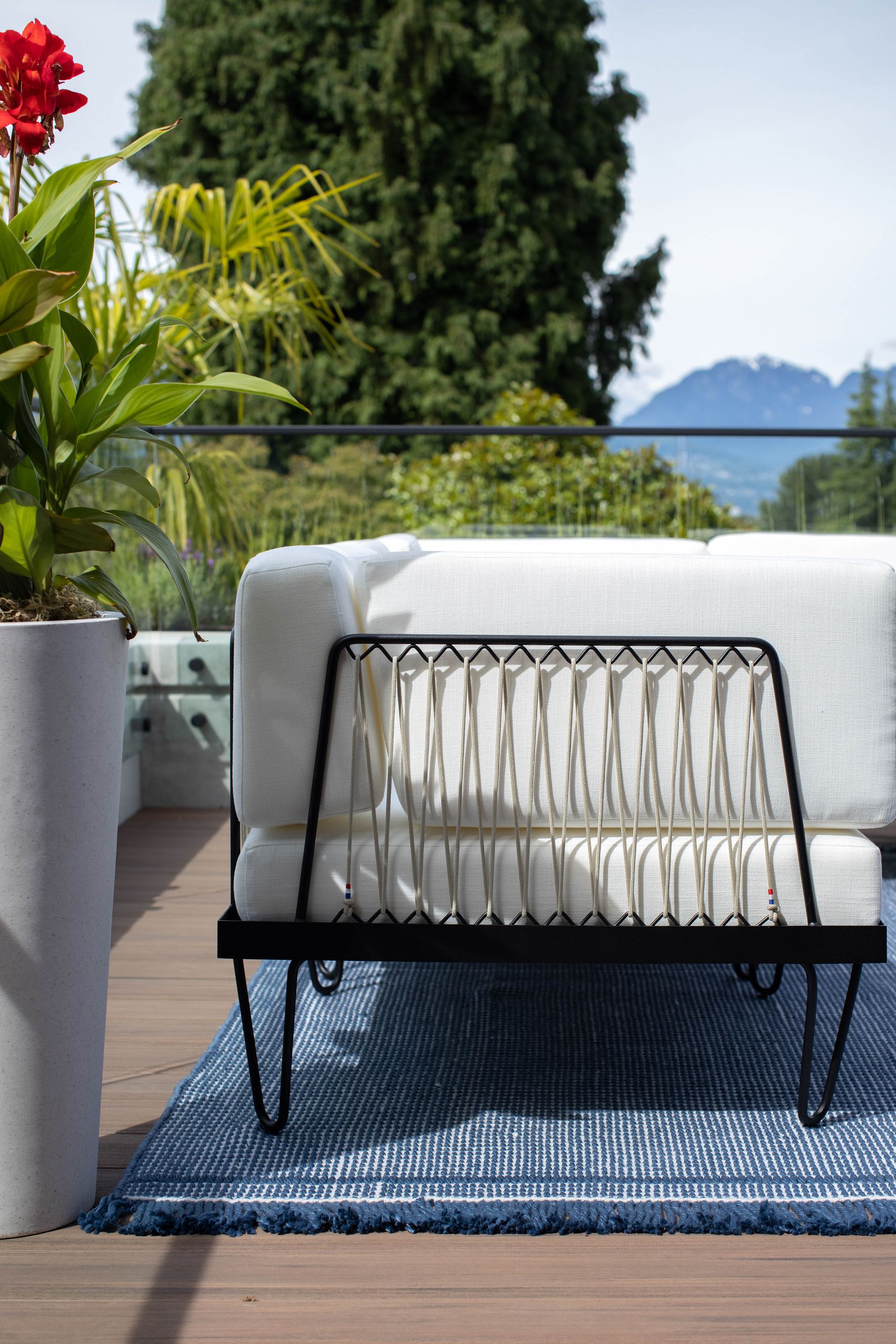 Rope-backed sofa on a blue flatweave rug, with the mountains beyond