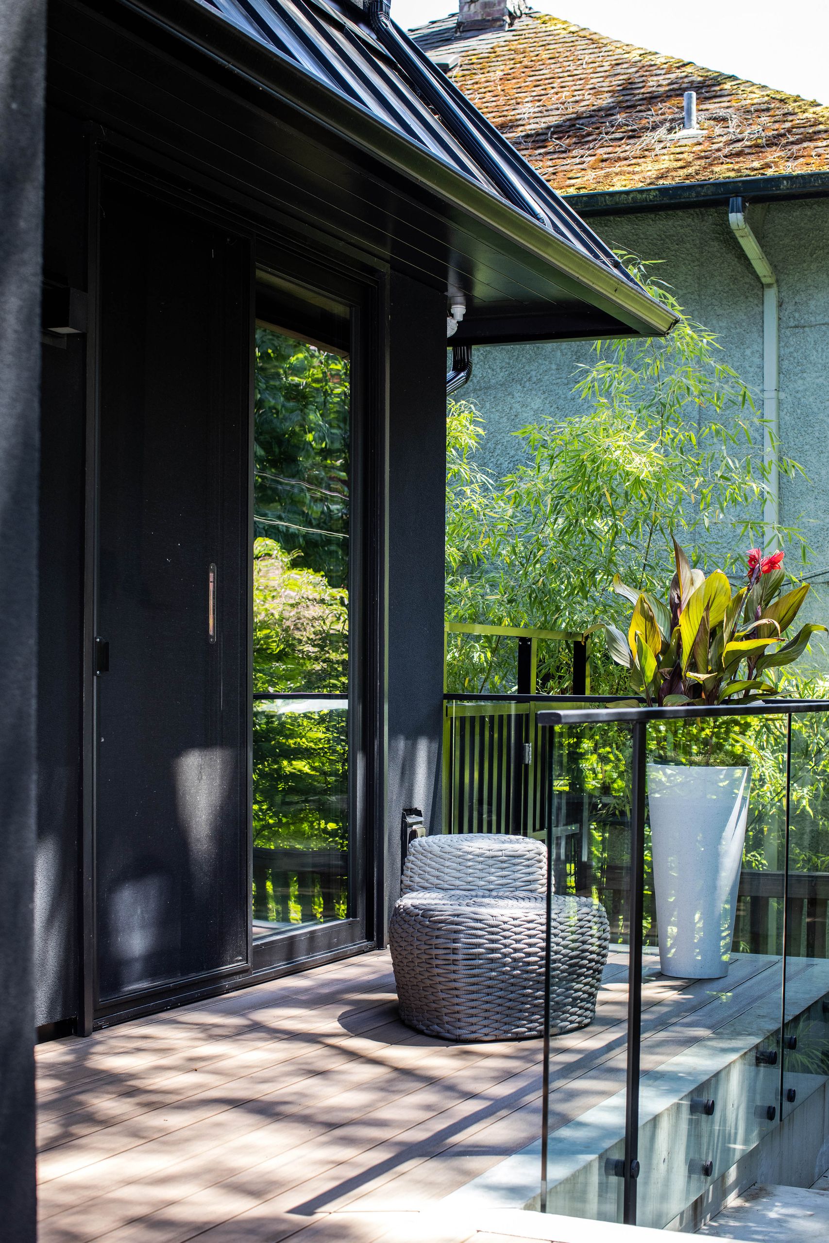 Upper deck corner with woven ottomans and a tall planter of canna