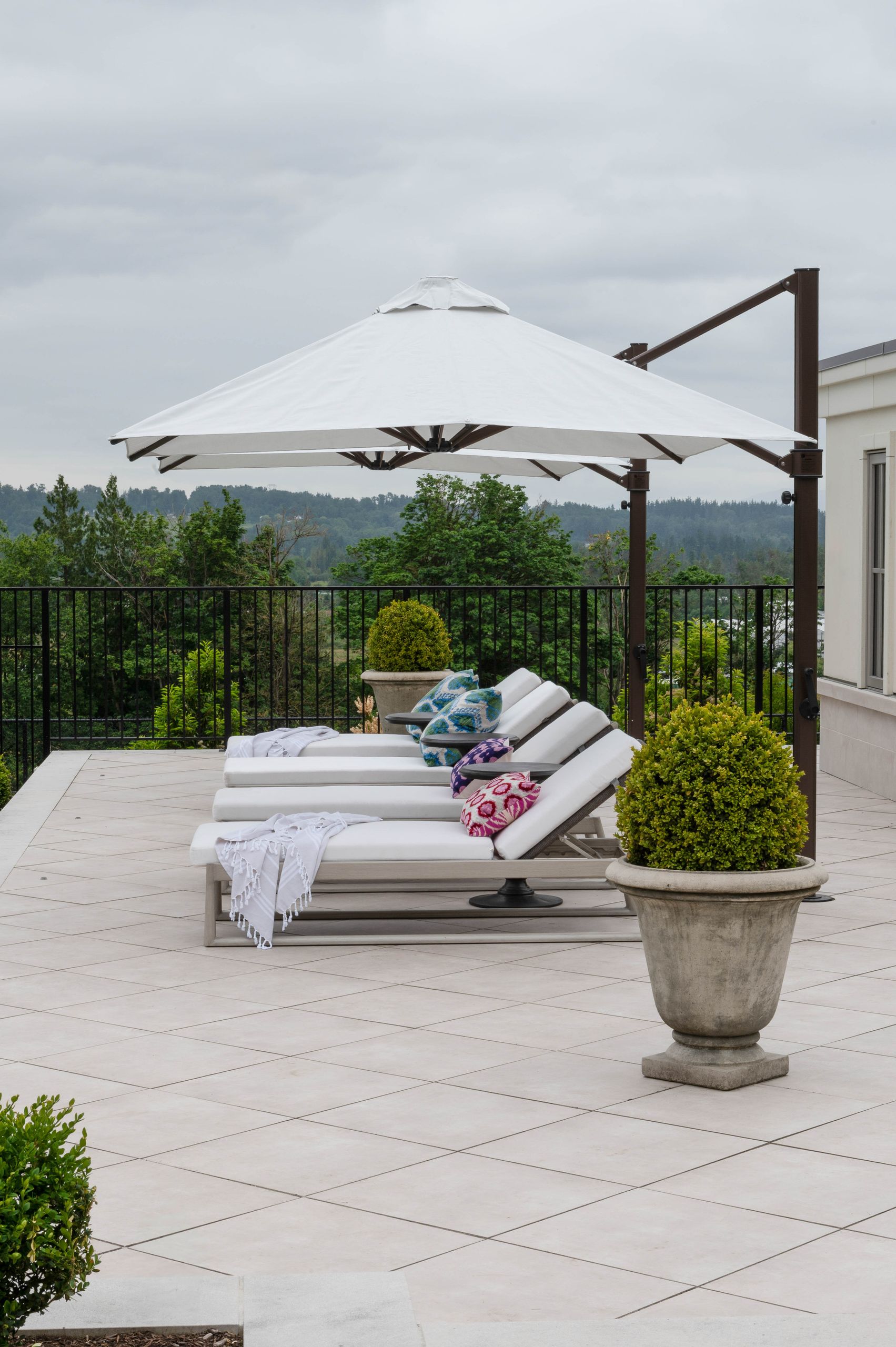 Four chaise longues beneath a cantilever umbrella on the limestone terrace