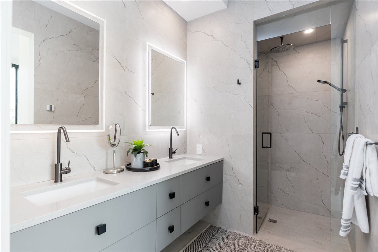 Ensuite with a double vanity, backlit mirrors and a glass shower in marble-look porcelain