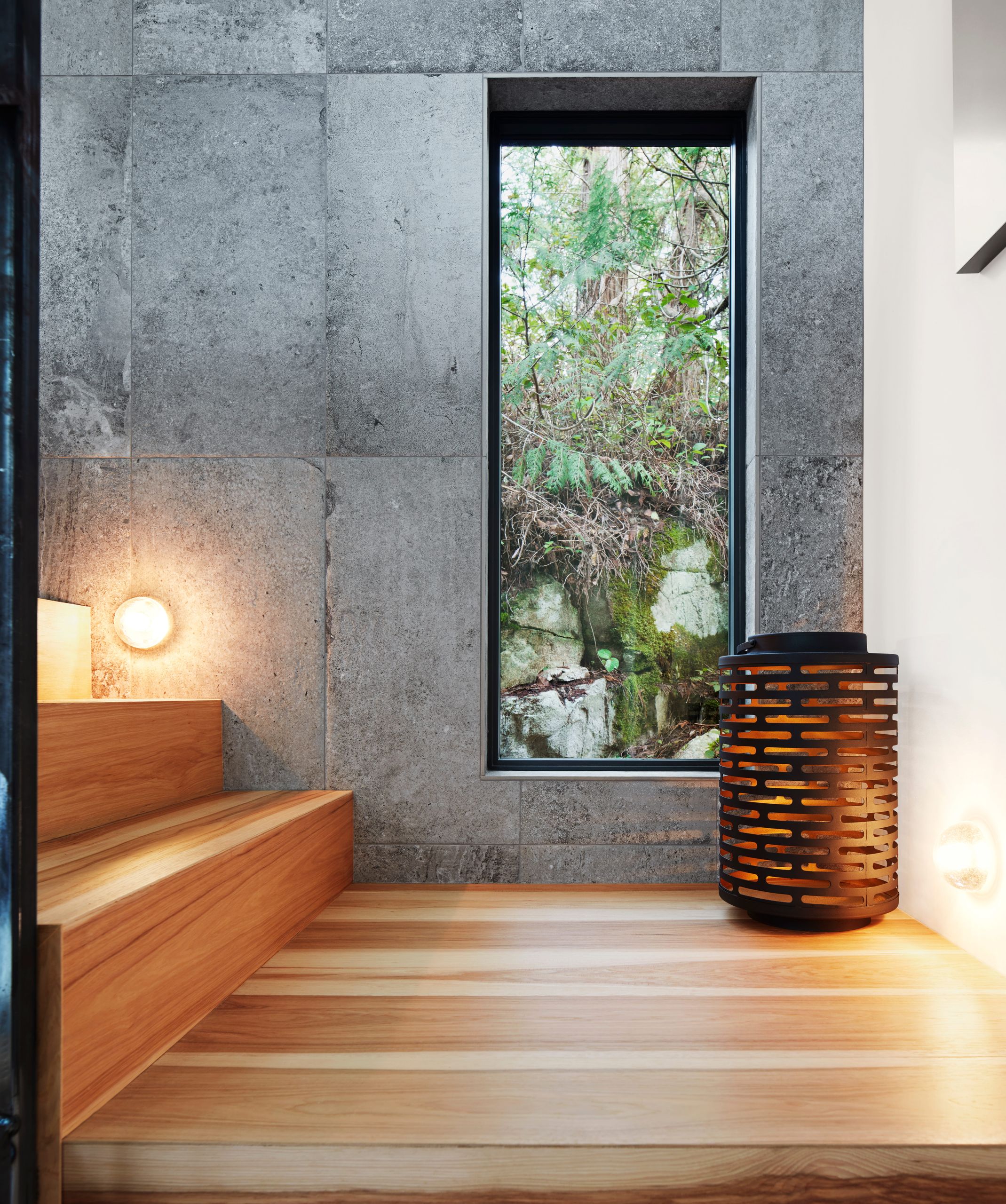 Sauna entry with cedar benches, stone tile and a slot window onto the forest