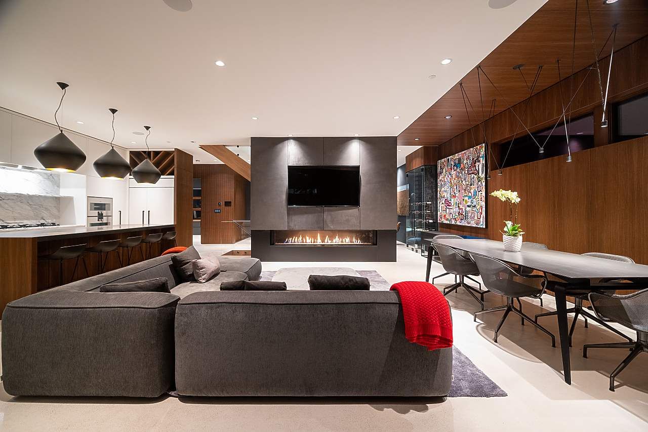 Open-plan living and dining space with a linear gas fireplace and walnut panelling